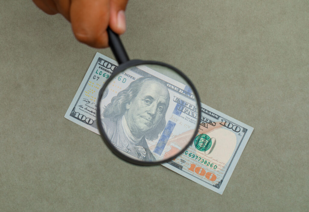 hand-holding-magnifying-glass-banknote-for-checking-hidden-costs-for-data-analysis-services